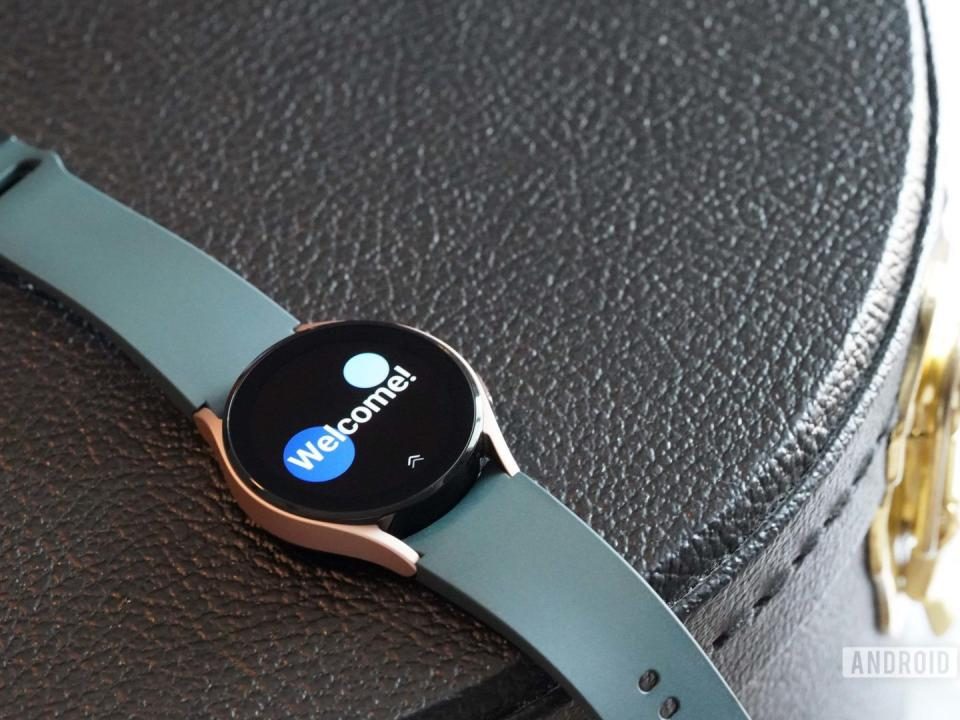 El Samsung Galaxy Watch 4 descansa sobre un estuche de cuero negro que muestra la pantalla de bienvenida del reloj.
