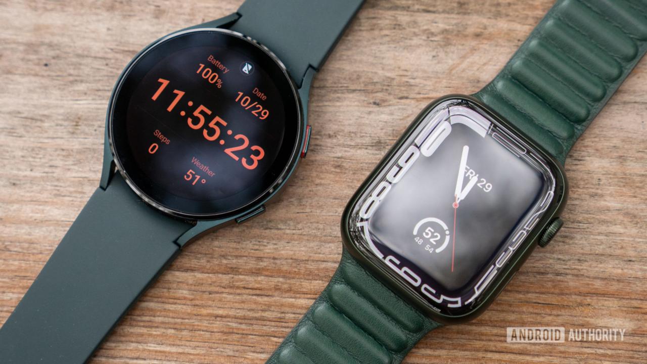 Un Apple Watch Series 7 y un Galaxy Watch 4 descansan uno al lado del otro sobre una superficie de madera, cada uno mostrando su esfera de reloj.