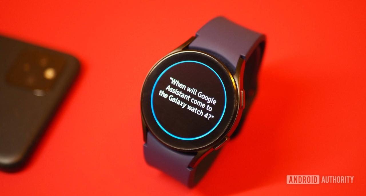 Samsung Galaxy Watch 4 sobre fondo rojo, mostrando una pregunta de Bixby sobre el Asistente de Google